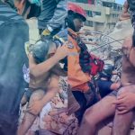 Rescatista llora junto a joven tras sacarlo de entre los escombros en Venezuela